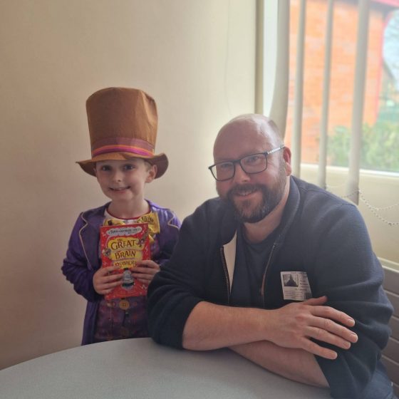 P.G. Bell with a young reader dressed as Willy Wonka, holding a copy of The Great Brain Robbery