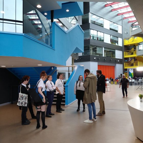 Director Andrew Creak addresses the cast in the college atrium. It's a large, airy space with a glass ceiling.