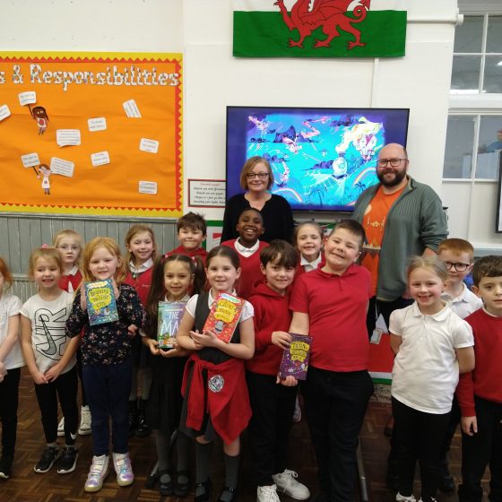 P.G. Bell, Jayne from Storyville Bookshop, and pupils from Trawllng Infants School pose together in the school hall